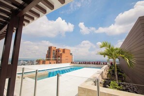Piscina no terraço com vista ampla para o horizonte urbano e o oceano.