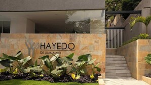 Een modern gebouw met een gevel van natuursteen en een bord waarop “HAYEDO DE JUANAMBU” staat.