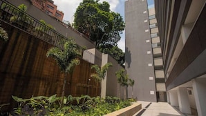 Un edificio moderno con un patio que presenta un muro de madera, barandilla metálica y diversas plantas.