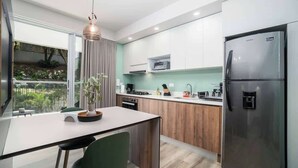 A modern kitchen with a built-in refrigerator, a dining area with a table and chairs, and a view of greenery outside. - H401 | top-Rated Cali Retreat 2BR w/ Balcony & Pool 24/7 Security + Free Parking (Cali)