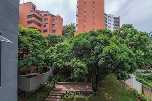 Zona residencial con una escalera que lleva a un jardín en la azotea, rodeada de abundante vegetación y edificios altos.