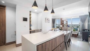 A modern kitchen with a central island, pendant lighting, and a view to the outside. - H604 - Beautiful View with Balcony, Pool & Parking (Cali)