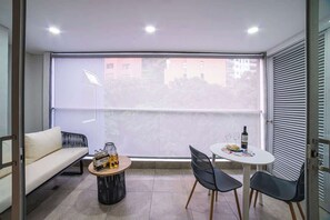 Uma varanda com um sofá, uma mesa redonda e duas cadeiras.