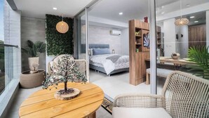 A modern bedroom with a bed, a wooden side table, and a large window. - H702 - Amazing Balcony | Pool | Gym | Near Granada (Cali)