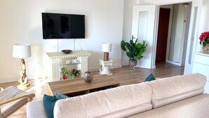 A modern living room with a flat-screen TV, a fireplace, and a sofa.