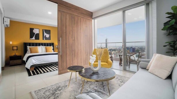 A modern hotel room with a bed, a sofa, a dining area, and a balcony with a city view. - H706 - Stylish 2BR / Perfect Views & Rooftop Pool (Cali)