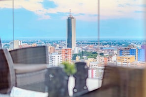 Vista panorámica de la ciudad desde un edificio alto, con un rascacielos destacado en la lejanía.