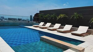 A rooftop pool with lounge chairs and palm trees. - H807 - Amazing Penthouse Views, Pool and Parking (Cali)