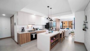 Una cocina moderna con armarios blancos, una isla central e iluminación colgante.