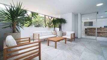 Un espace intérieur moderne avec un canapé en bois, deux fauteuils en bois, une table basse et des plantes en pot.