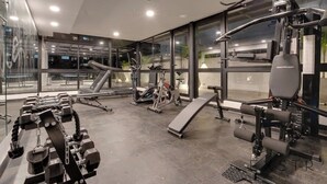 A modern gym with various exercise equipment, large windows, and a view of the outside. - RM 1102 | Luxurious Suite | Pool | Gym | Security (Cali)