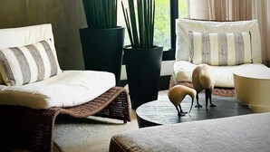 Un salon moderne avec une grande fenêtre, deux canapés, une table basse et une plante en pot.