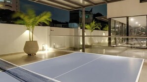 Een indoor pingpongtafel met een glazen scheidingswand en potplanten.