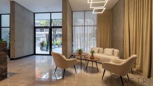 Een modern interieur met een bank, twee fauteuils, een salontafel en een groot raam met gordijnen.