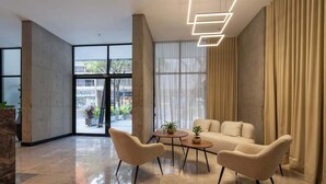 Un interior moderno con zona de estar, un ventanal con cortinas y vistas al exterior.