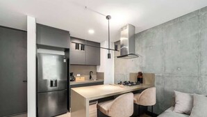 A modern kitchen with a built-in refrigerator, a gas stove, and bar stools. - RM 208 | Gorgeous 1-Bed | Parking | Pool | Sauna (Cali)