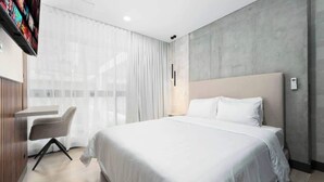 A modern hotel room with a large bed, a desk, and a TV mounted on the wall. - RM 208 | Gorgeous 1-Bed | Parking | Pool | Sauna (Cali)