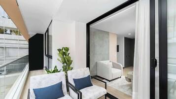 Un salon moderne avec un balcon, une grande plante et une vue sur la ville.