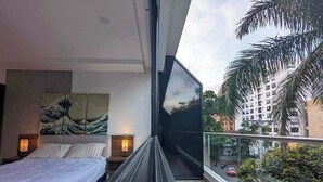 A modern bedroom with a large bed, a painting, and a view of a cityscape through a balcony. - Dazzling Brand-New 1 BD w Terrace & Pool (Cali)