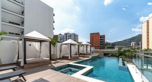 Un espace piscine aménagé sur le toit, avec des chaises longues et des cabanas.