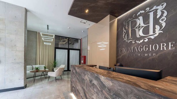 A reception area with a marble counter, a modern chandelier, and a seating area with a sofa and chairs. - RM 309 | Perfect Studio | Luxury Amenities | Pool (Cali)
