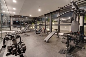 A modern gym with various exercise equipment, large windows, and a clean, well-lit interior. - RM 309 | Perfect Studio | Luxury Amenities | Pool (Cali)