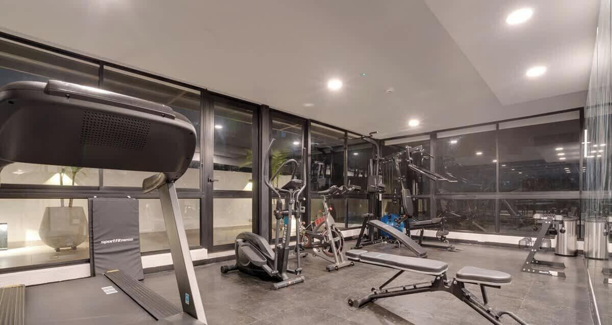 Et moderne fitnesscenter med forskellig træningsudstyr, store vinduer og et rent, veloplyst interiør.
