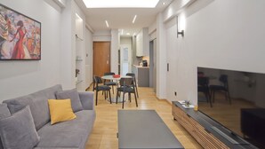 A modern living room with a grey sofa, a coffee table, and a flat-screen TV. - Stylish Ilisia Stay Luxury Fully Reno 2BR, 2BA Apt (Athens)