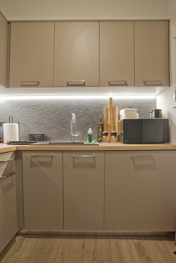 A modern kitchen with a central island, a built-in oven, and a stainless steel sink.