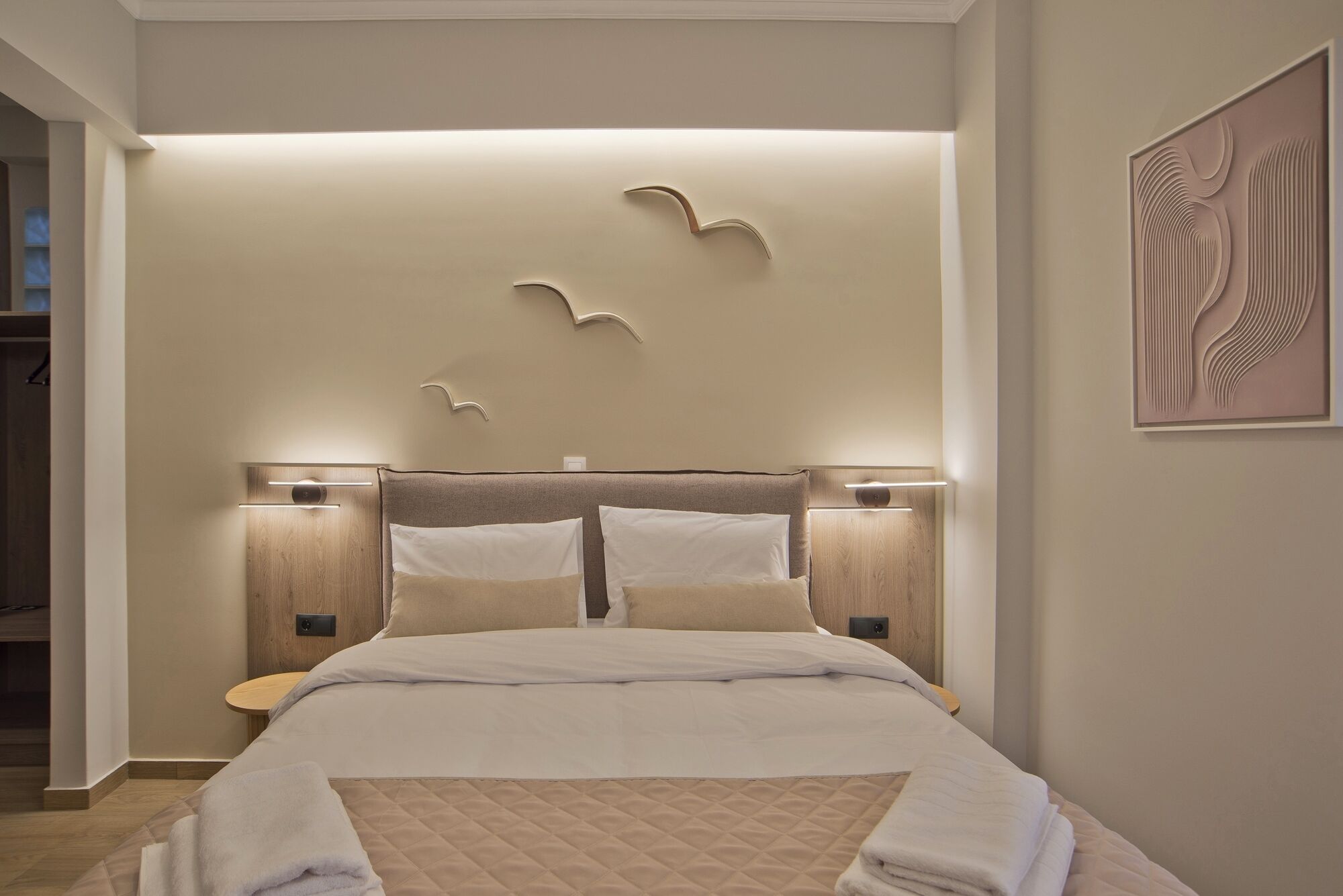 A neatly made bed with a quilted cover, two bedside tables, and a wall-mounted light fixture.