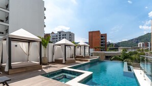 A rooftop pool area with a clear view of the surrounding buildings and mountains.