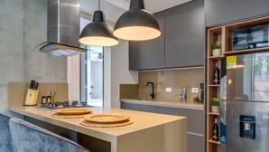 A modern kitchen with a central island, pendant lighting, stainless steel appliances, and a built-in wine cooler.