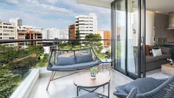 Un balcón con sofá, sillas y una mesa, con vistas a un paisaje urbano.