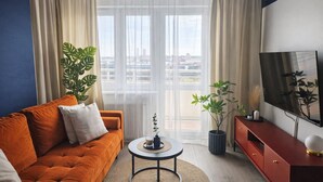 Un salon moderne avec un canapé, une table basse, un téléviseur et des plantes en pot.