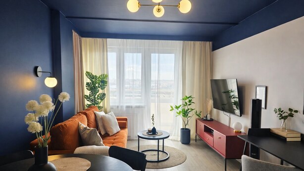 Un salon moderne avec un canapé, une table basse, un téléviseur et des plantes.