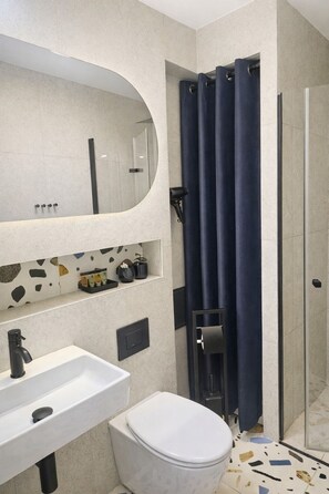 A bathroom with a white sink, a toilet, a mirror, and a shower with a dark curtain. - Apartament Gwarek - by Kairos Apartments (Katowice)