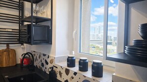 Une cuisine moderne équipée d’une cuisinière intégrée, d’une bouilloire et d’une fenêtre donnant sur la ville.