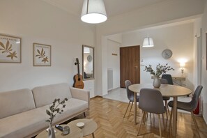 Ein modernes Wohnzimmer mit einer Couch, einem Esstisch mit Stühlen, einer Gitarre und gerahmten Kunstwerken an der Wand.