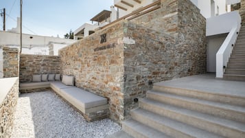 A stone wall with a built-in bench and steps leading up to a modern building.