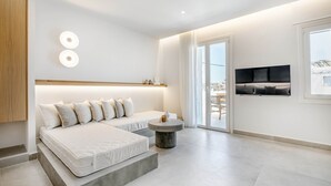 Een moderne slaapkamer met een groot bed, een klein rond tafeltje en een aan de muur bevestigde televisie.