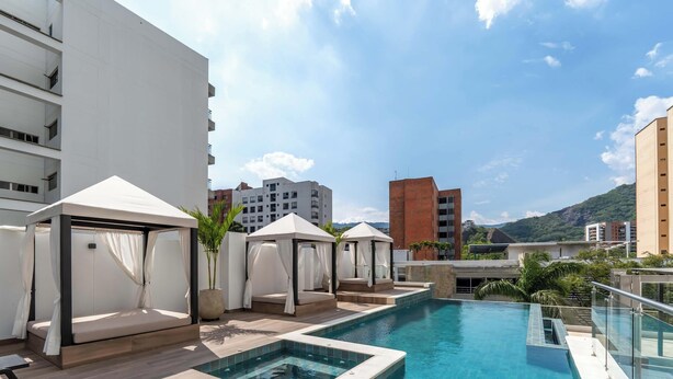 A rooftop pool area with a clear view of the surrounding buildings and a mountain in the background. - RM902| LuxeHigh- Hideaway – Pool, Sauna & Security (Cali)