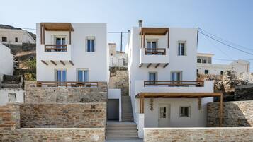 A modern two-story building with a stone facade, wooden balconies, and a staircase leading to the entrance.