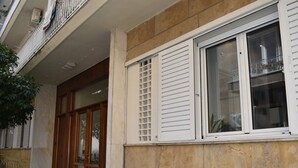 Eine Gebäudefassade mit Steinverkleidung, einer Holztür und einem Fenster mit weißen Fensterläden.