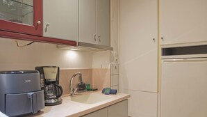 Eine kleine Küche mit Kaffeemaschine, Spüle und Kühlschrank.