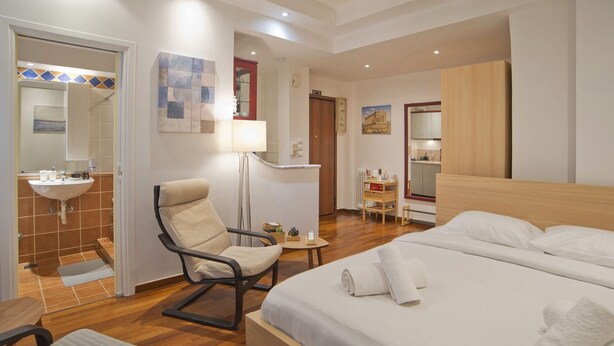 Ein Hotelzimmer mit Bett, Stuhl, Schreibtisch, Waschbecken und einer kleinen Küchenzeile.