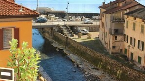 Μια θέα προς το ποτάμι, με κτίρια, μια γέφυρα και βουνά στο βάθος.