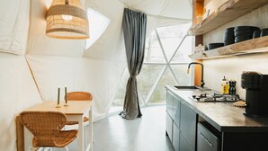 Alojamiento con carpa, zona de comedor, cocina y ventanas grandes.
