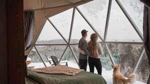 Una habitación con carpa, una cama, una silla y vistas a un paisaje nevado.