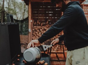A person grilling outdoors with a large pot on the grill.