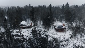 Dos cabañas en forma de domo geodésico en un bosque nevado.
